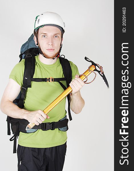 Mountain tourist in helmet and with big backpack standing and holding pick. Mountain tourist in helmet and with big backpack standing and holding pick