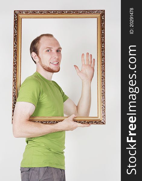 Man in green shirt holding decorative picture frame and smiling. Man in green shirt holding decorative picture frame and smiling