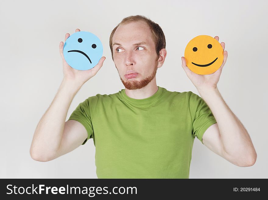 Young man in green shirt holding emotion smile symbols. Young man in green shirt holding emotion smile symbols