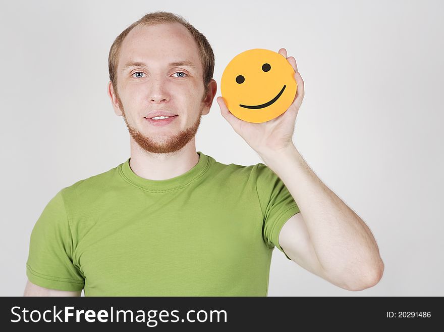 Young man in green shirt holding emotion smile card. Young man in green shirt holding emotion smile card