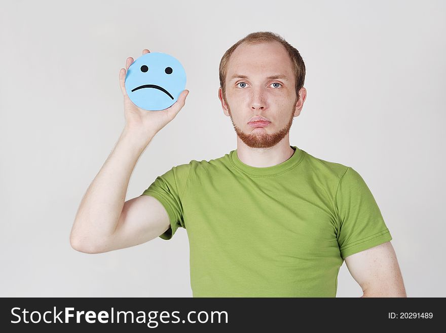 Young man in green shirt holding emotion sadness card. Young man in green shirt holding emotion sadness card