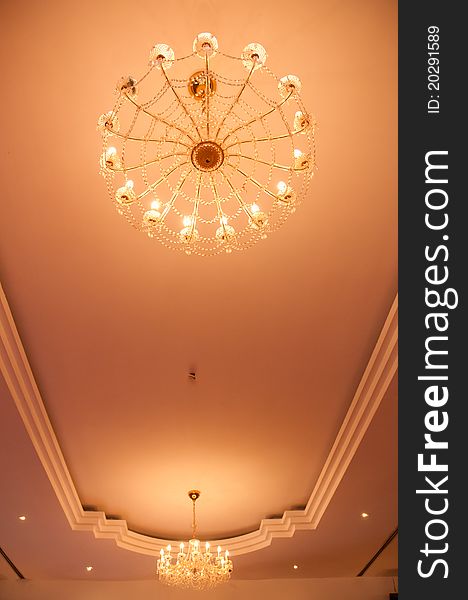 Chandelier lights with pattern like spider webs on ceiling of a ballroom