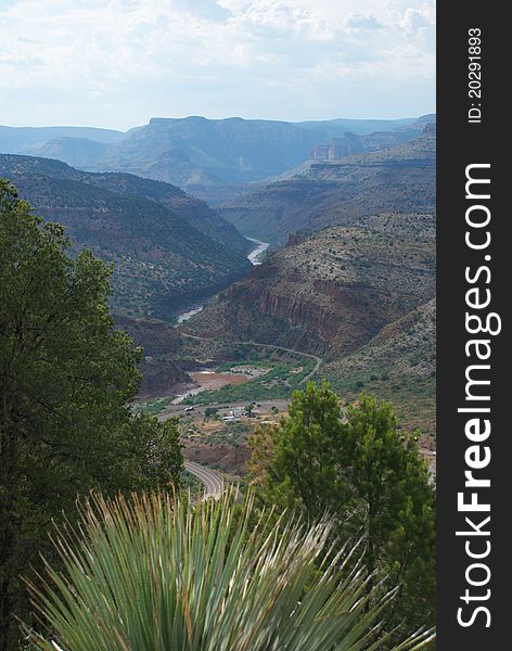 Beautiful Desert View with Winding River and road below with white clouds and mountain vistas and plants in a canyon. Beautiful Desert View with Winding River and road below with white clouds and mountain vistas and plants in a canyon