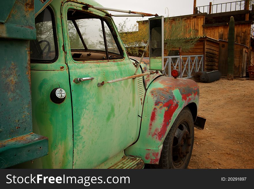 A Rusty old truck with patches of green and red paint in an old western town. A Rusty old truck with patches of green and red paint in an old western town