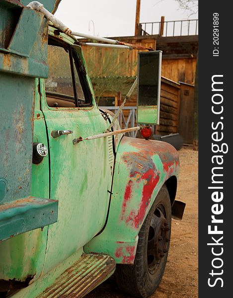 A Rusty old truck with patches of green and red paint in an old western town. A Rusty old truck with patches of green and red paint in an old western town