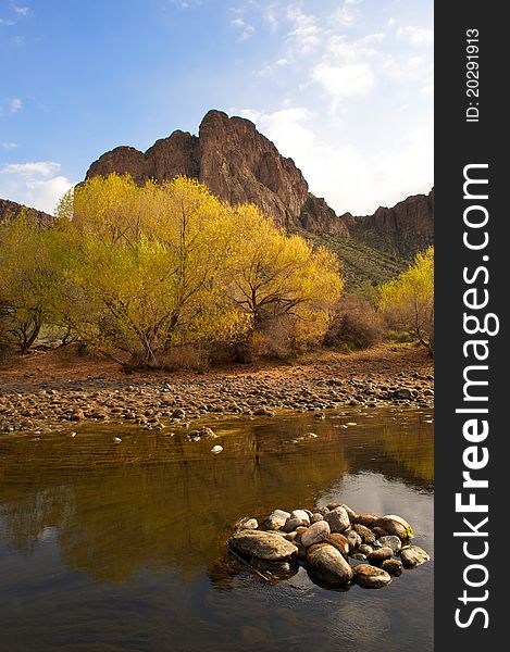 Peaceful River with Beautiful Yellow Tree and Desert Mountains and green plants with stones and reflection