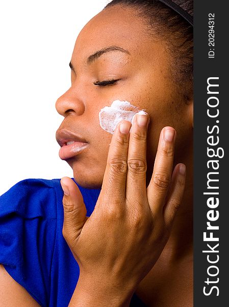 A young woman applying cream to her face. A young woman applying cream to her face.