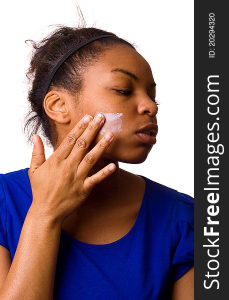 A young woman applying cream to her face. A young woman applying cream to her face.