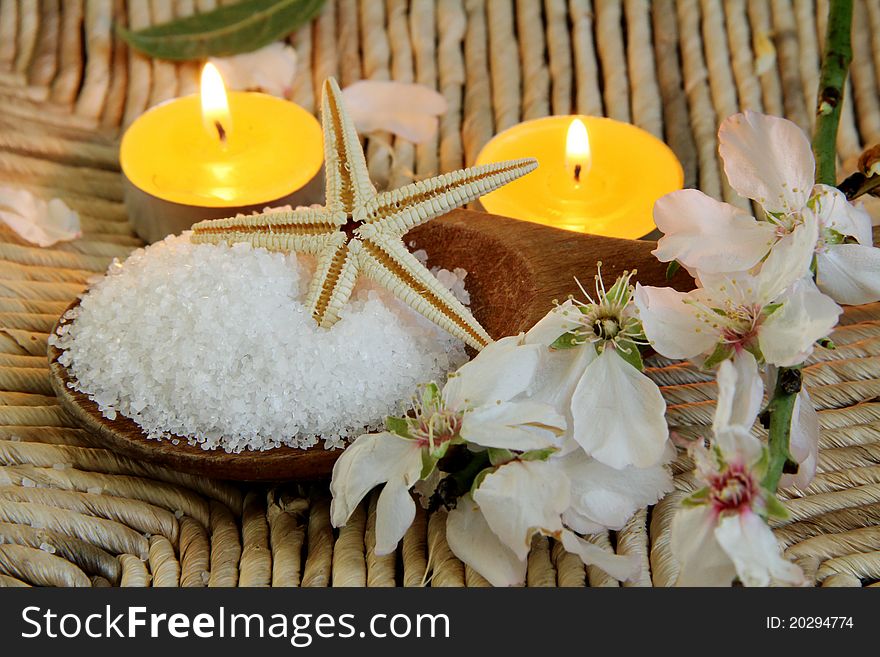 Closeup of Healthy Sea Salt with a branch of an almond tree on bamboo background. Spa background