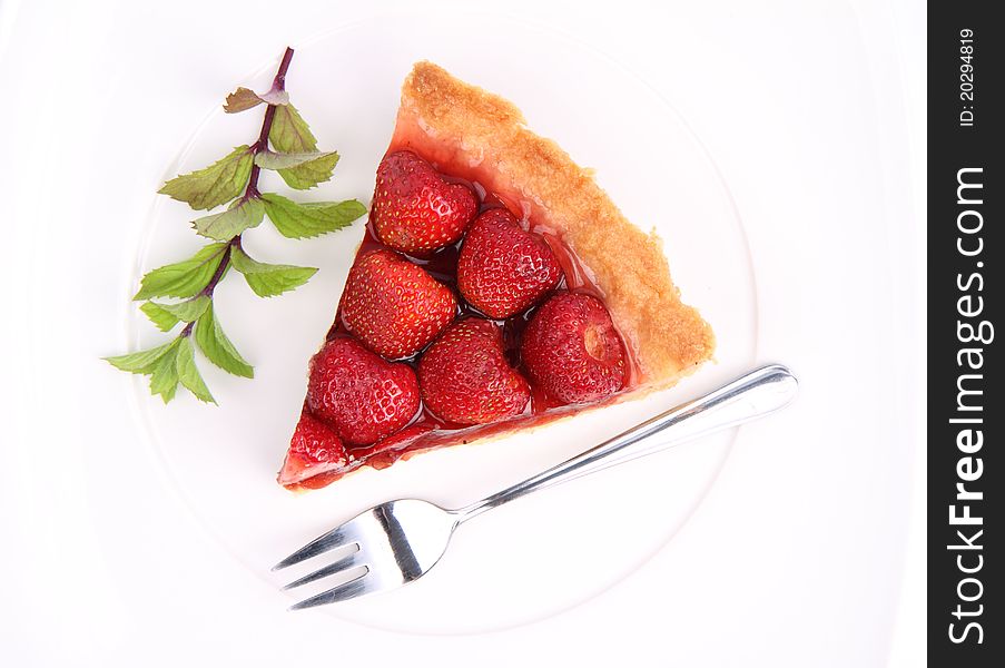 Piece of Strawberry Tart on white plate decorated with mint twig