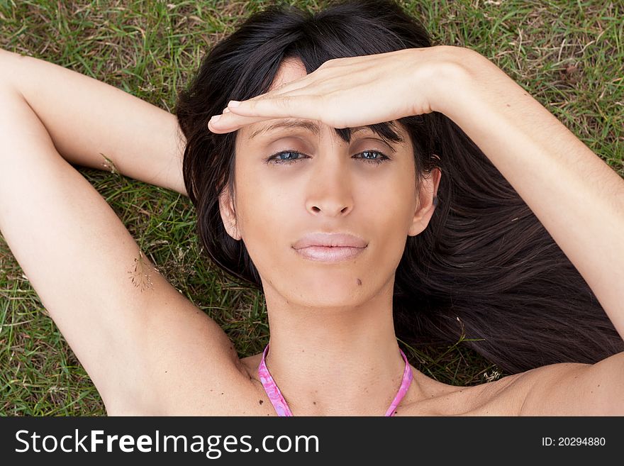 An attractive brunette lying on the grass on the park facing with her face to the sky. An attractive brunette lying on the grass on the park facing with her face to the sky