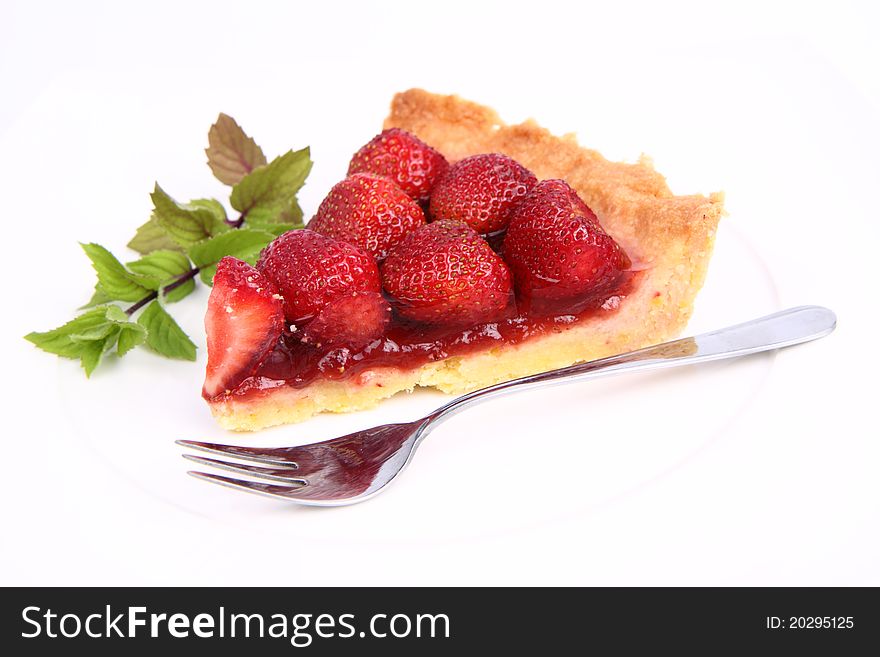 Piece of Strawberry Tart on white plate decorated with mint twig