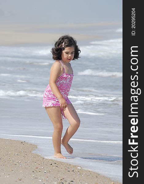 Little girl on the beach running in the coastline