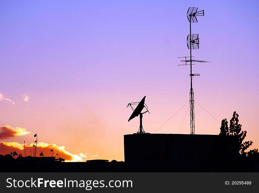 Two antennas in a building and some plants during sunset. Two antennas in a building and some plants during sunset