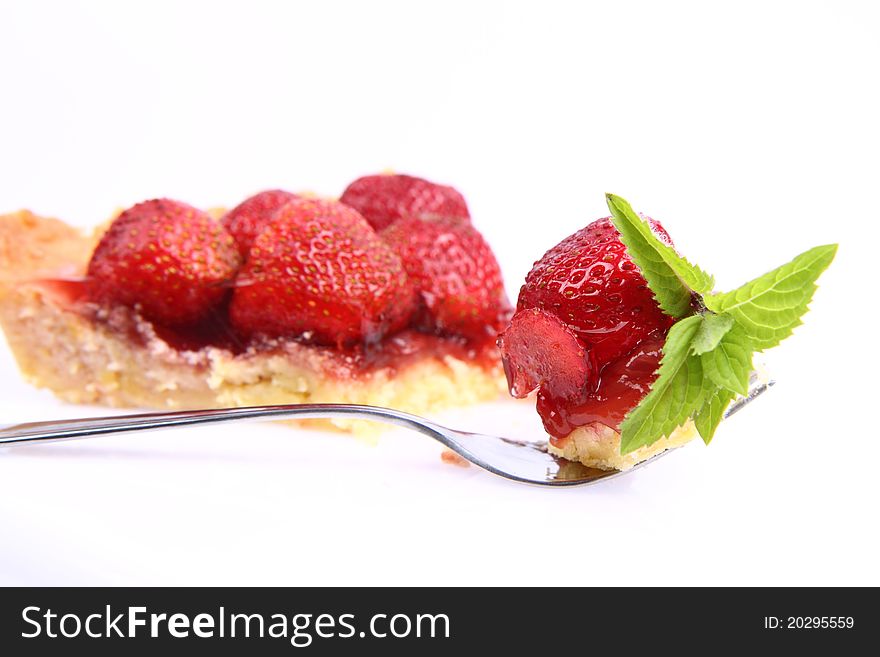 Piece of Strawberry Tart on white background , some on a fork decorated with mint twig