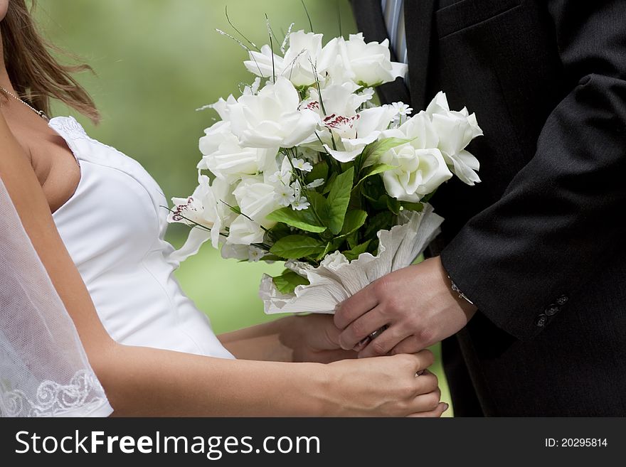 Photo of bride and groom's hands holding wedding bouquet. Photo of bride and groom's hands holding wedding bouquet