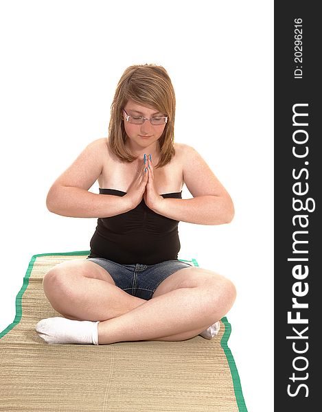 Young teenager sitting on a mad and concentrating on her yoga session
with glasses and her eyes closed, for white background. Young teenager sitting on a mad and concentrating on her yoga session
with glasses and her eyes closed, for white background.