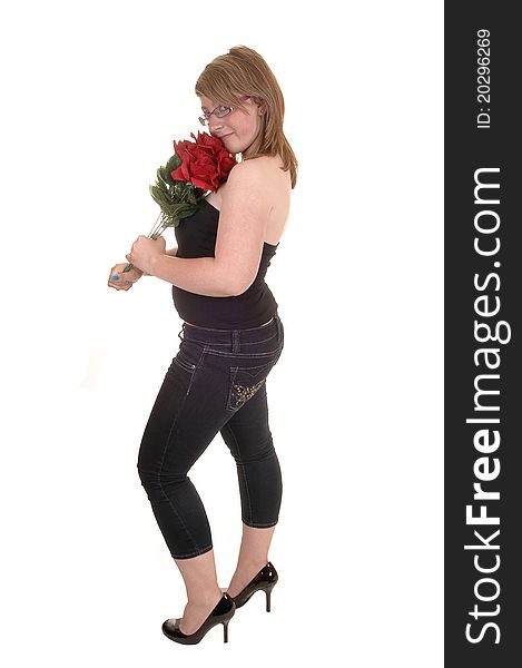 A pretty teenager standing in profile for white background, holding a bunch of red roses in her hand, in jeans and high heels. A pretty teenager standing in profile for white background, holding a bunch of red roses in her hand, in jeans and high heels.