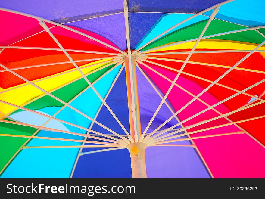 The underside of a rainbow colored beach umbrella.