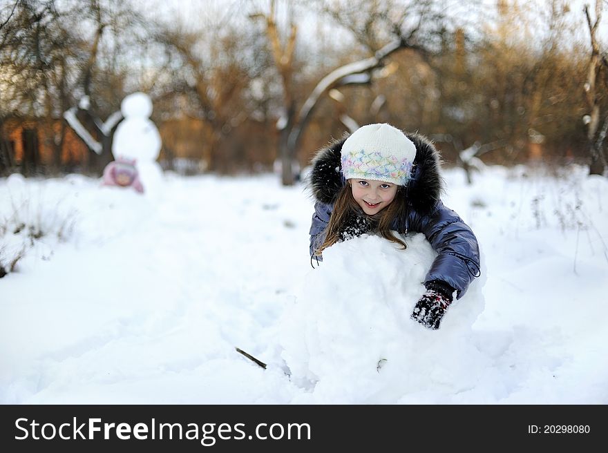 Little Girl rolling snow to make snowman