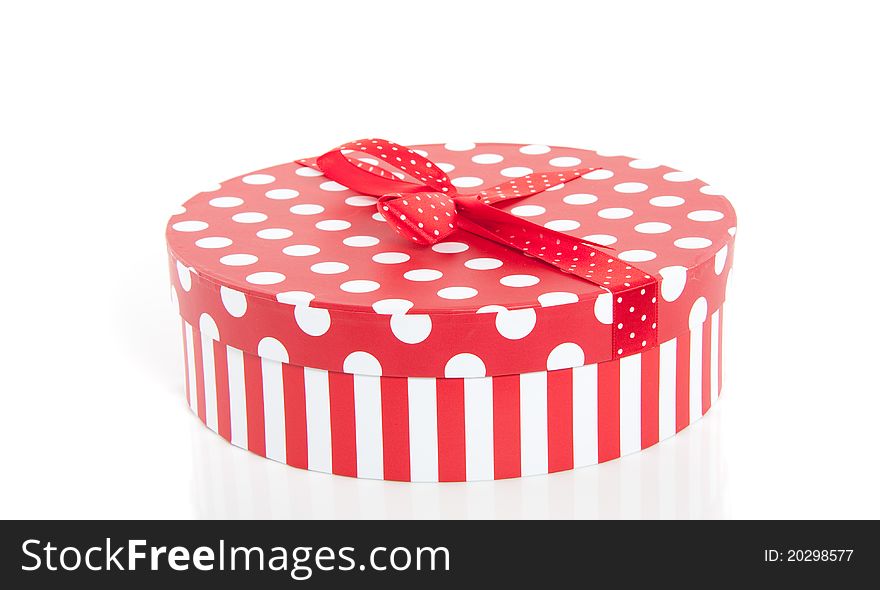 A red white dotted round cardbound box with stripes and a ribbon on top. A red white dotted round cardbound box with stripes and a ribbon on top