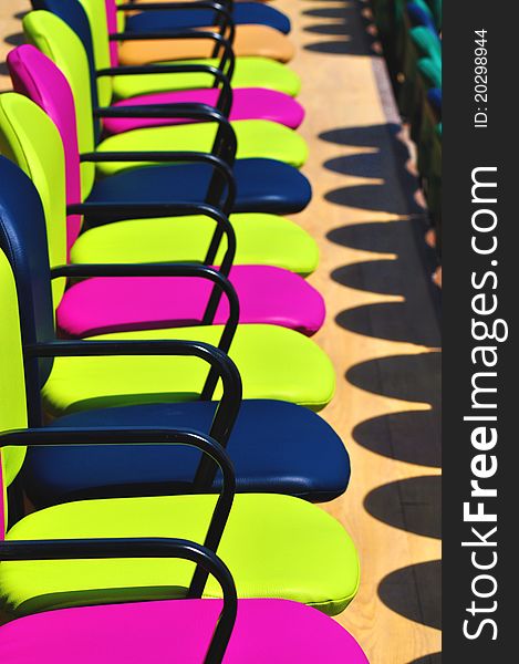 Chairs in many different colors aligned into rows. Chairs in many different colors aligned into rows.