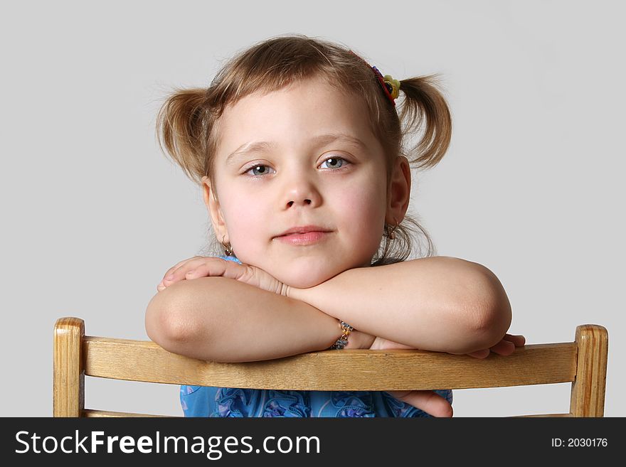 Small girl sits on chair, gray background. Small girl sits on chair, gray background