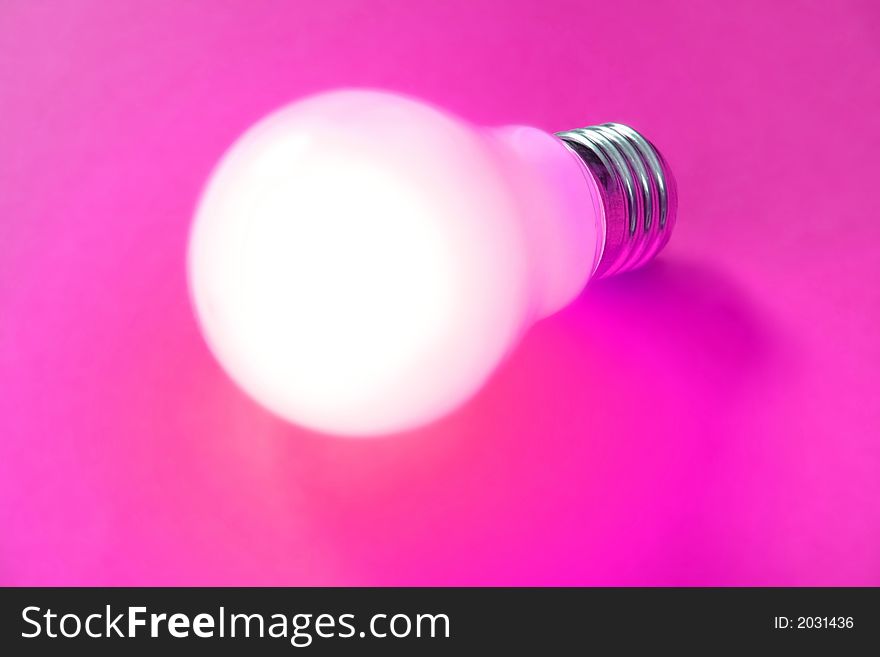 Illuminated lightbulb on magenta background