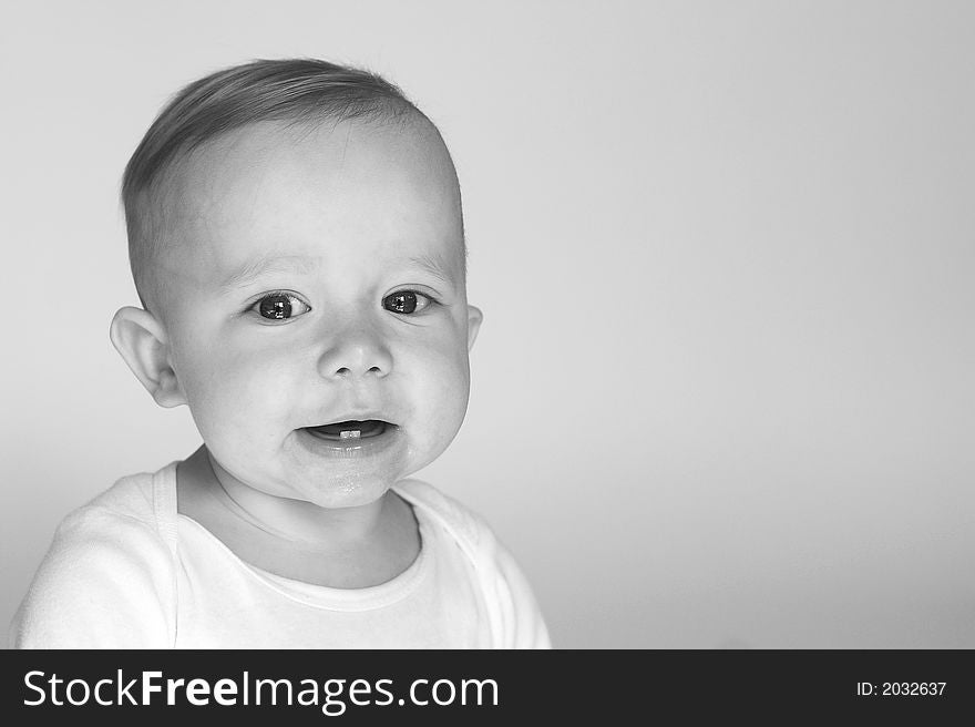 Black and white image of cute smiling baby sitting in front of a white background