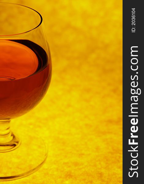 Half glass with red cognac on orange backgroung. Half glass with red cognac on orange backgroung
