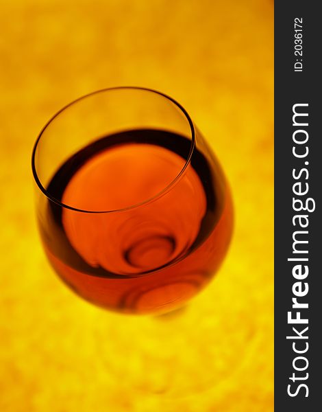 Glass with red cognac with orange background in perspective. Glass with red cognac with orange background in perspective