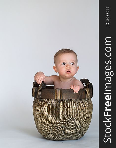 Black and white image of cute baby sitting in a woven basket. Black and white image of cute baby sitting in a woven basket