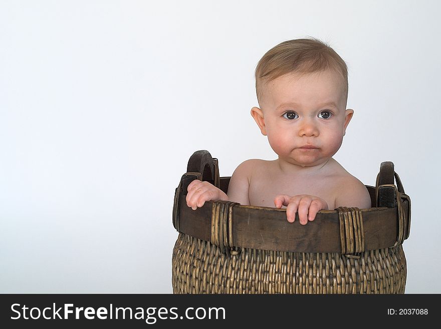 Black and white image of cute baby sitting in a woven basket. Black and white image of cute baby sitting in a woven basket