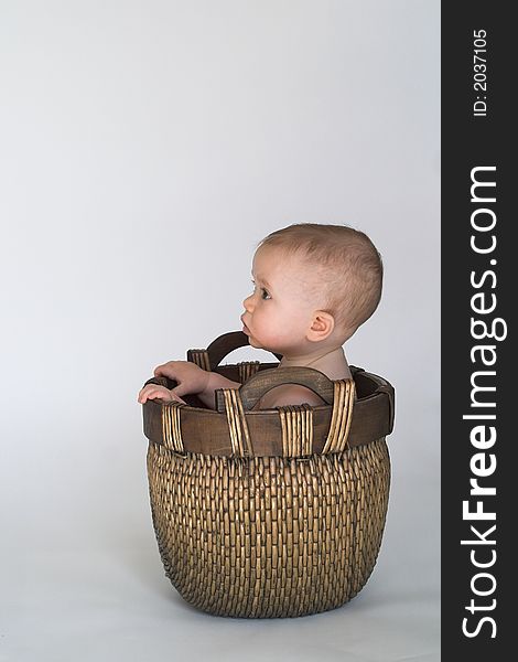 Black and white image of cute baby sitting in a woven basket. Black and white image of cute baby sitting in a woven basket