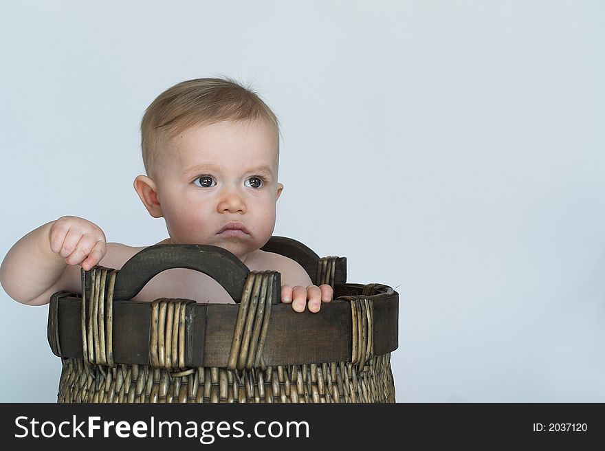 Black and white image of cute baby sitting in a woven basket. Black and white image of cute baby sitting in a woven basket