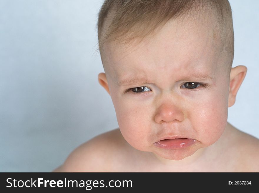 Image of cute whining baby sitting in front of a white background. Image of cute whining baby sitting in front of a white background