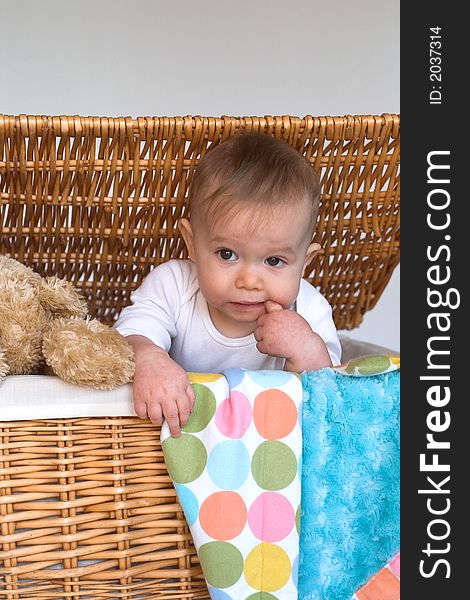 Image of cute baby and teddy bear peeking out of a wicker trunk