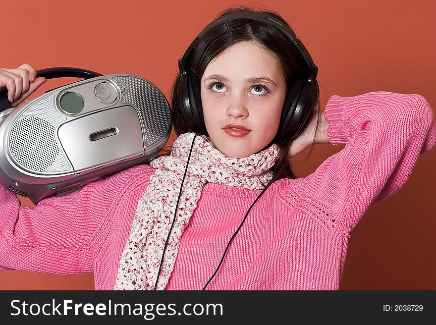 Pretty girl listening music with headphones and holding portable CD radio