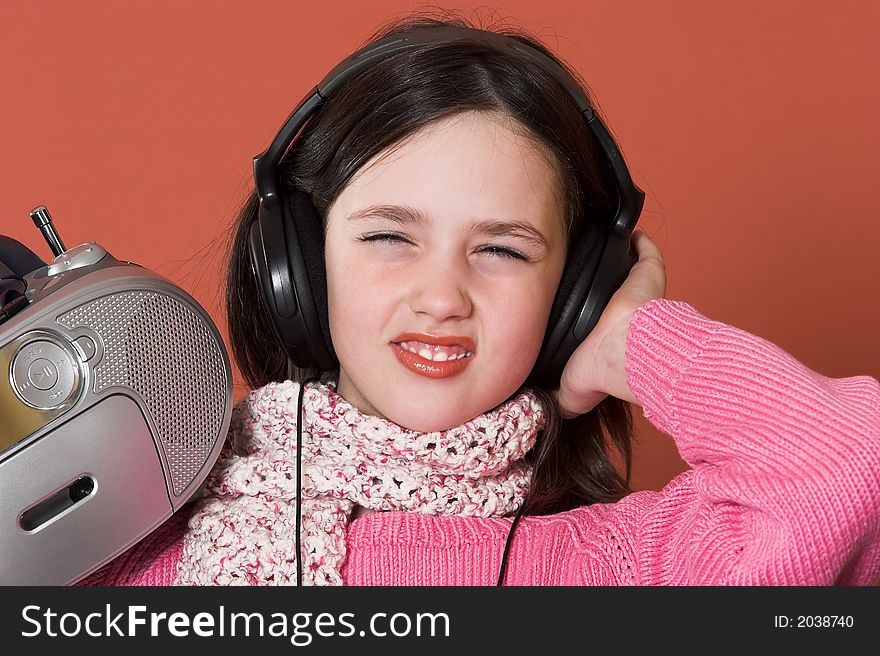 Pretty girl listening music with headphones and holding portable CD radio