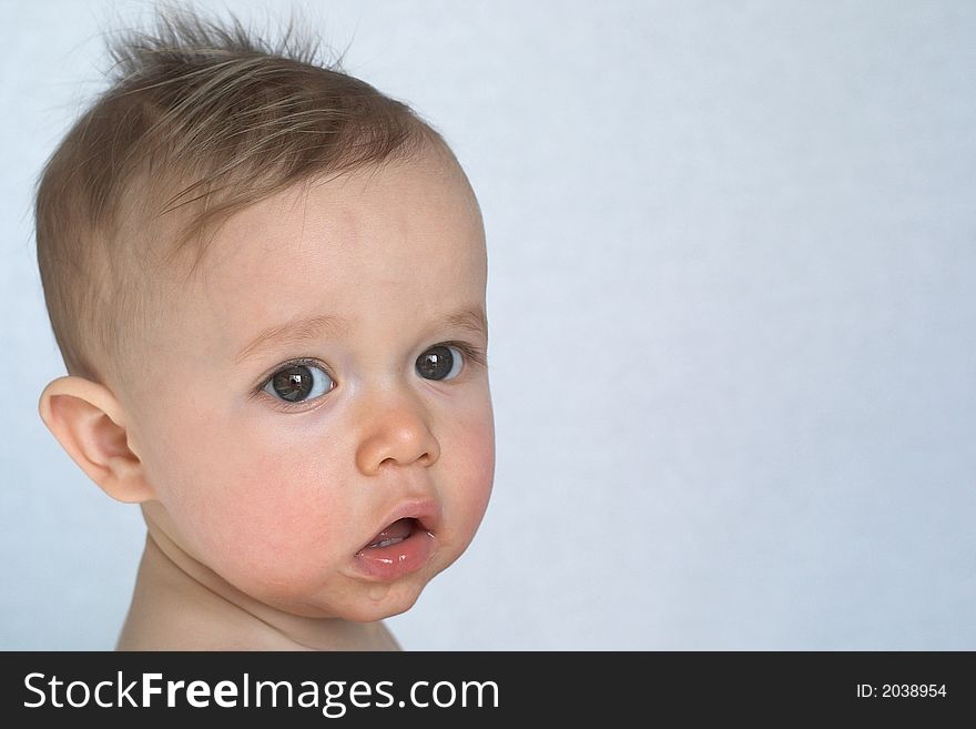 Image of a beautiful 10 month old baby boy sitting in front of a white background. Image of a beautiful 10 month old baby boy sitting in front of a white background