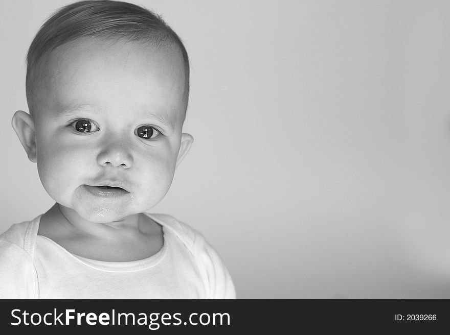 Black and white image of beautiful 10 month old baby boy sitting in front of a white background. Black and white image of beautiful 10 month old baby boy sitting in front of a white background