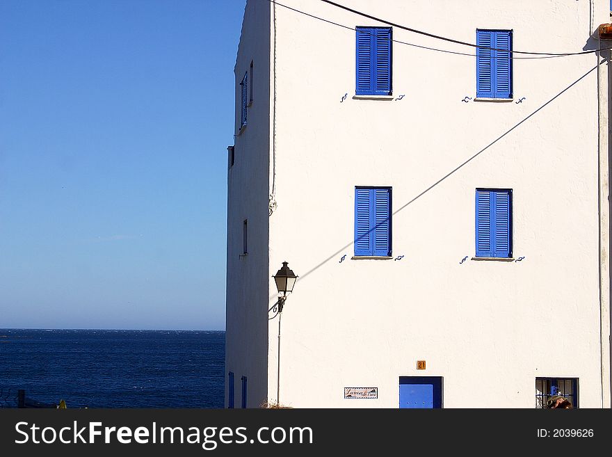 Typical house with blue windows and white wall in the town of Cadaques, Catalonia, Spain, Europe. Typical house with blue windows and white wall in the town of Cadaques, Catalonia, Spain, Europe