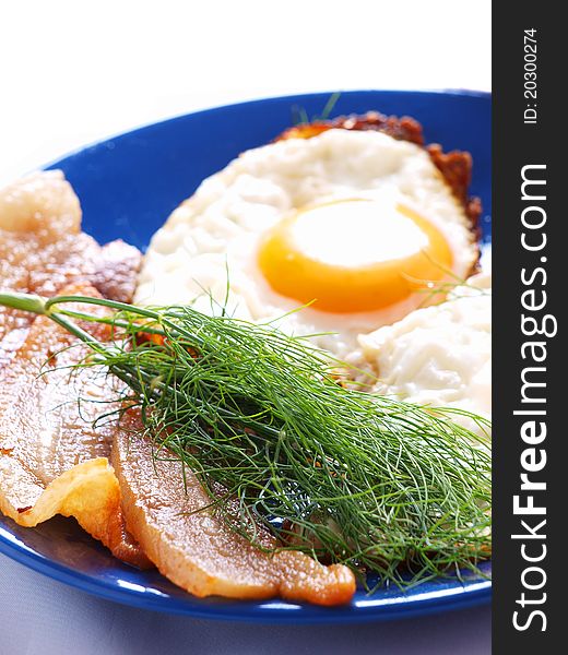 Fried eggs and bacon on a blue plate closeup. Fried eggs and bacon on a blue plate closeup