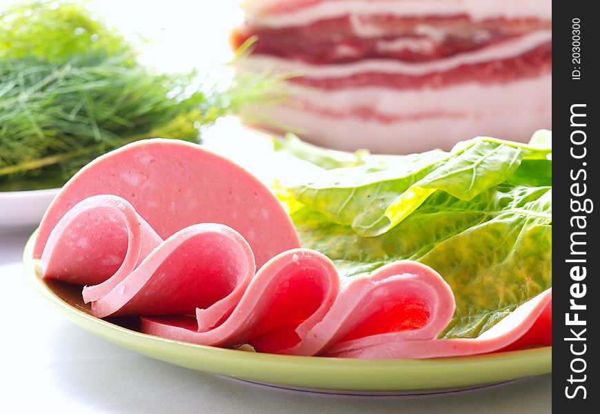 Sliced sausages on the background of a large piece of bacon