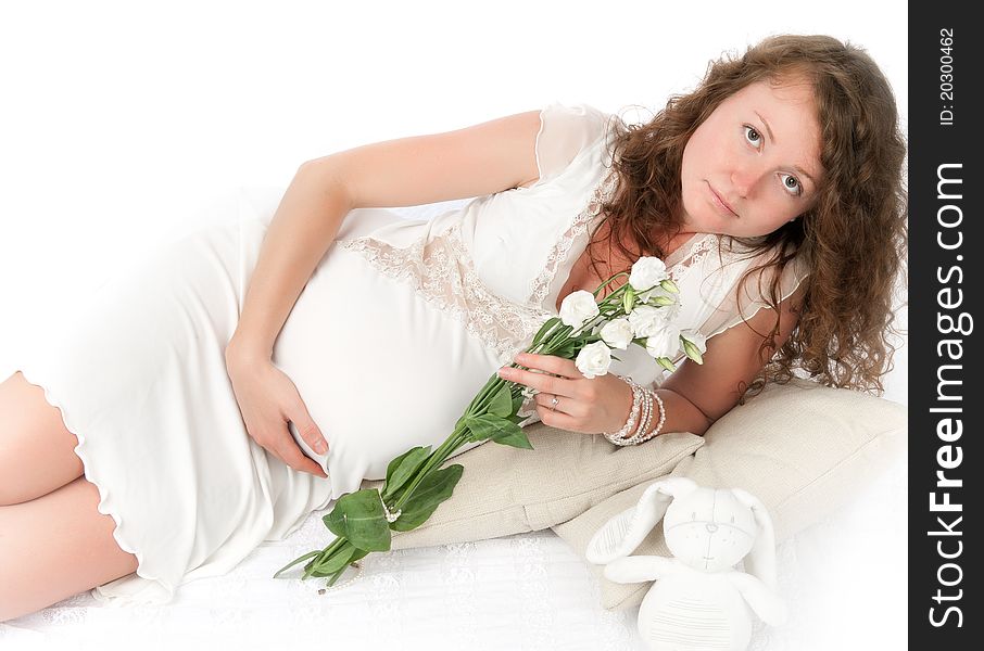 Pregnant young woman lies. Isolated on white