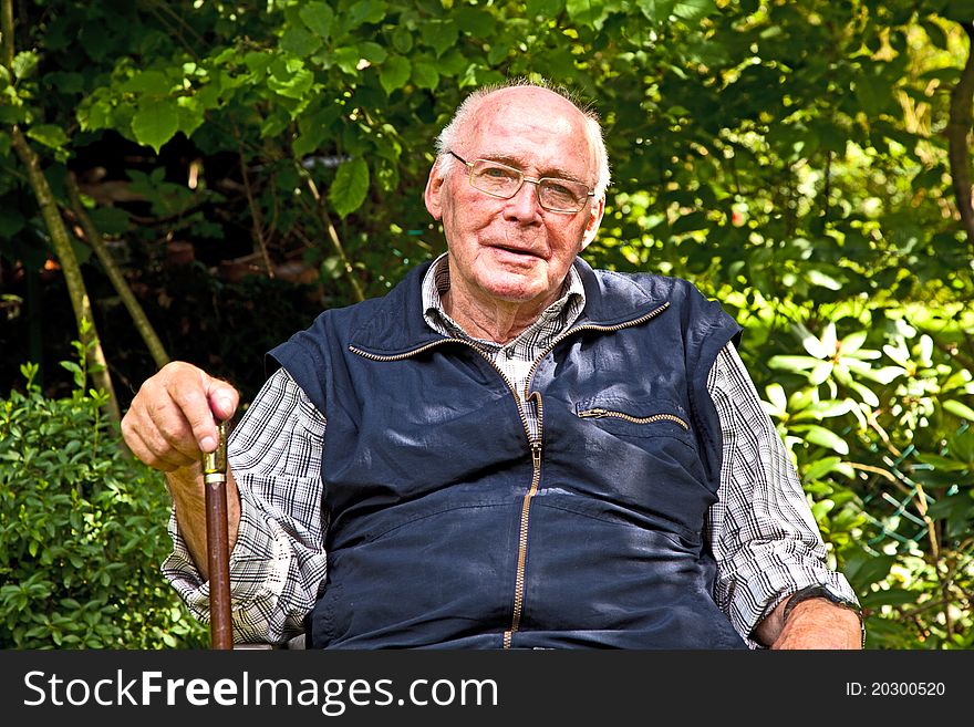 Portrait of elderly man sitting happy in his garden