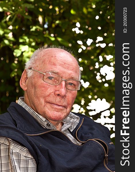 Portrait of elderly man sitting happy in his garden