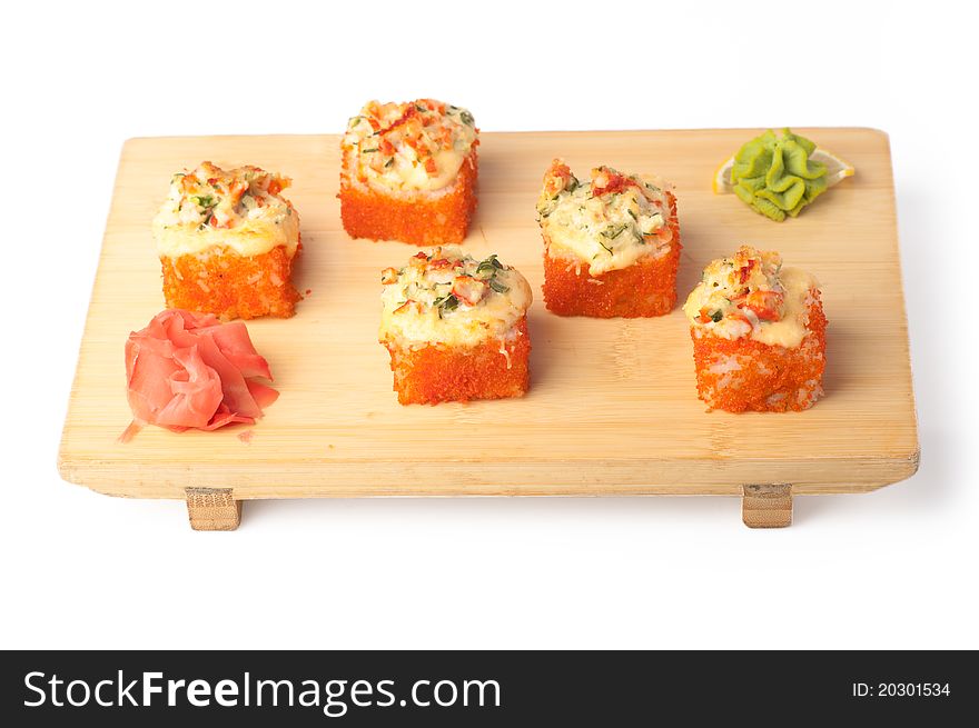 Wooden plate with four pieces of California rolls, wasabi and ginger