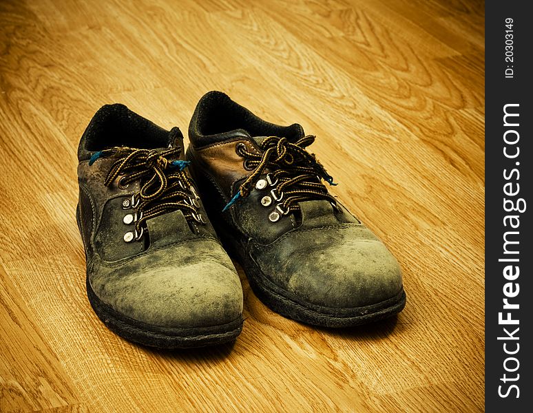 Pair of old used trekking boots on the wood background. Pair of old used trekking boots on the wood background