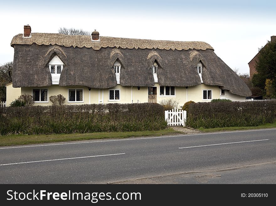 Front elevation of a thatched cottage with roof partly repaired